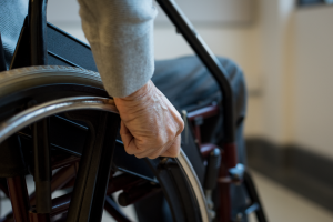 Man in a wheelchair with hand on wheel.